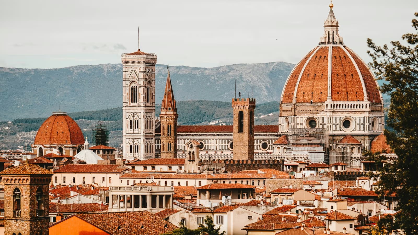 The dome of Florence Cathedral and Giotto's bell tower above the city's terracotta rooftops, with hills behind