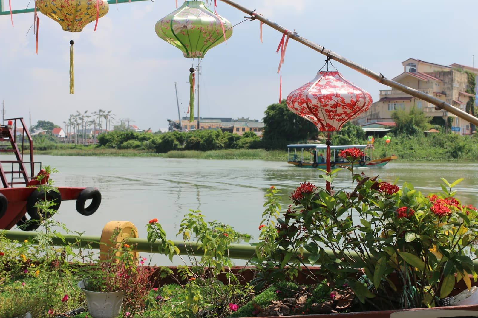 Silk lanterns hanging beside the river in Hoi An, with a tourist boat on the water