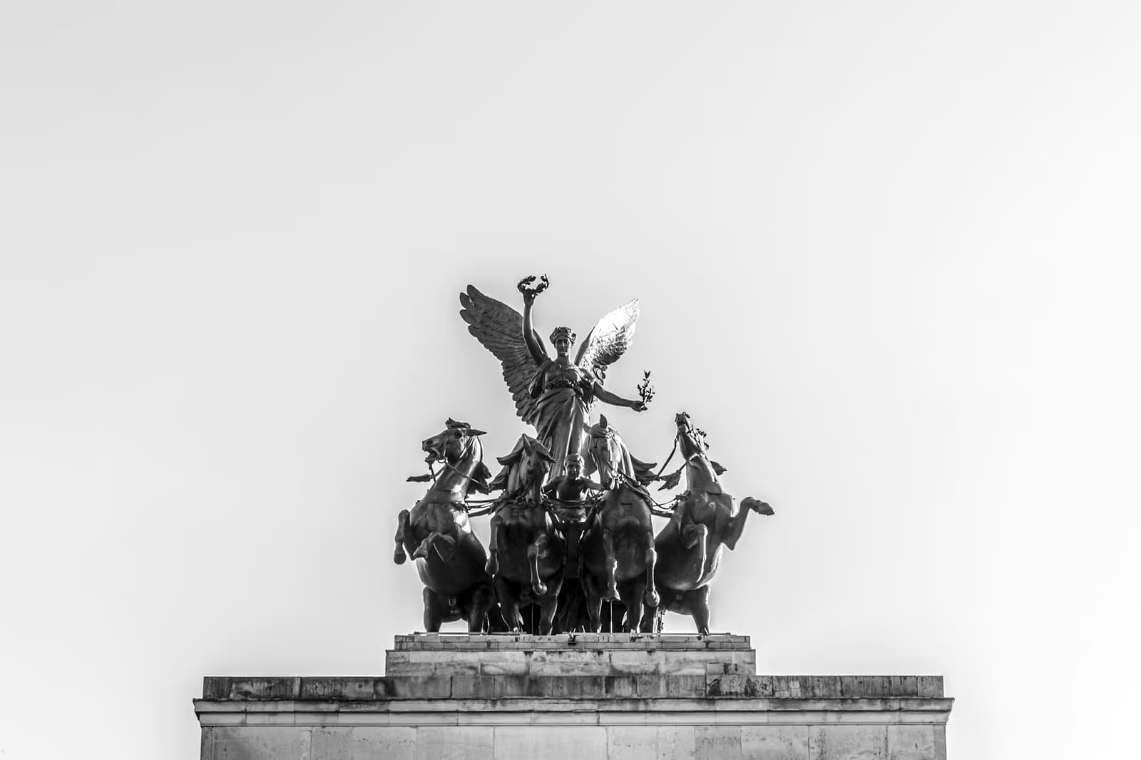 The bronze quadriga of a winged figure and four horses on top of Wellington Arch, against a pale sky