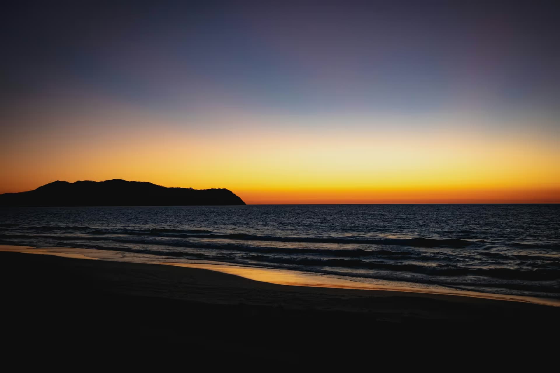 The sun setting behind a headland across the bay at Punta de Mita