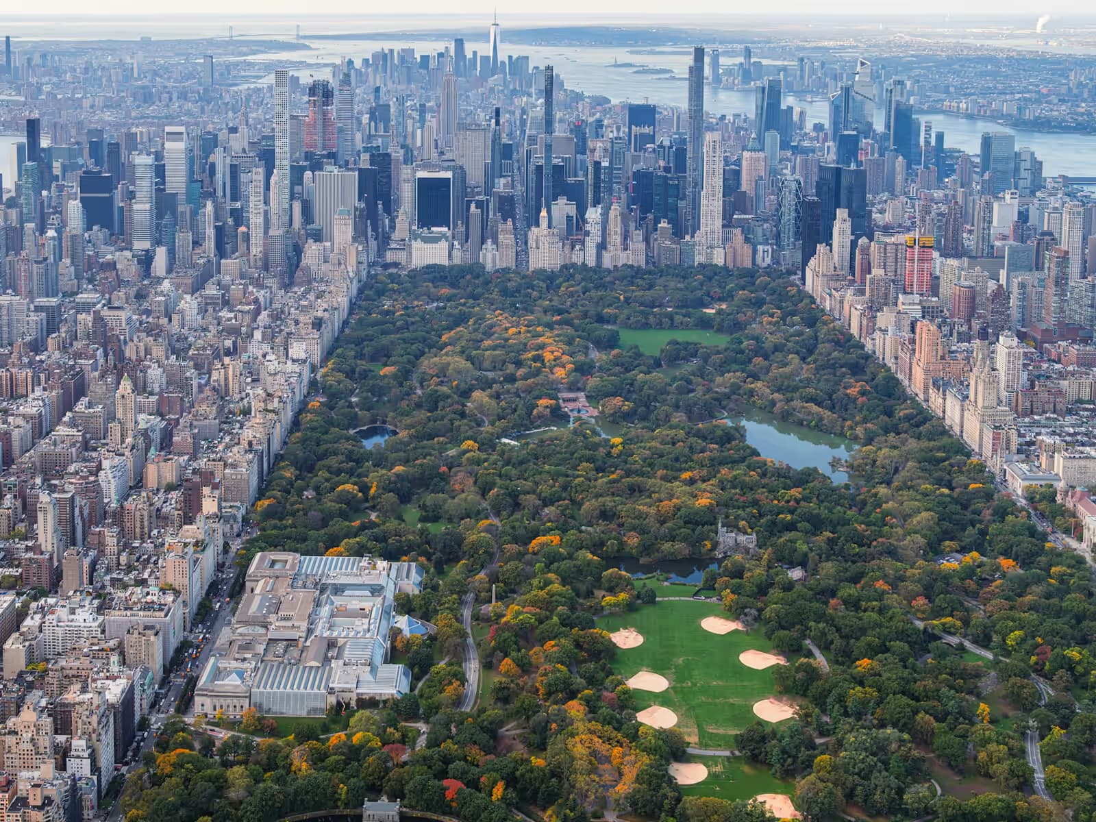 Central Park in autumn seen from the air, with the Metropolitan Museum of Art in the foreground and the Midtown towers beyond
